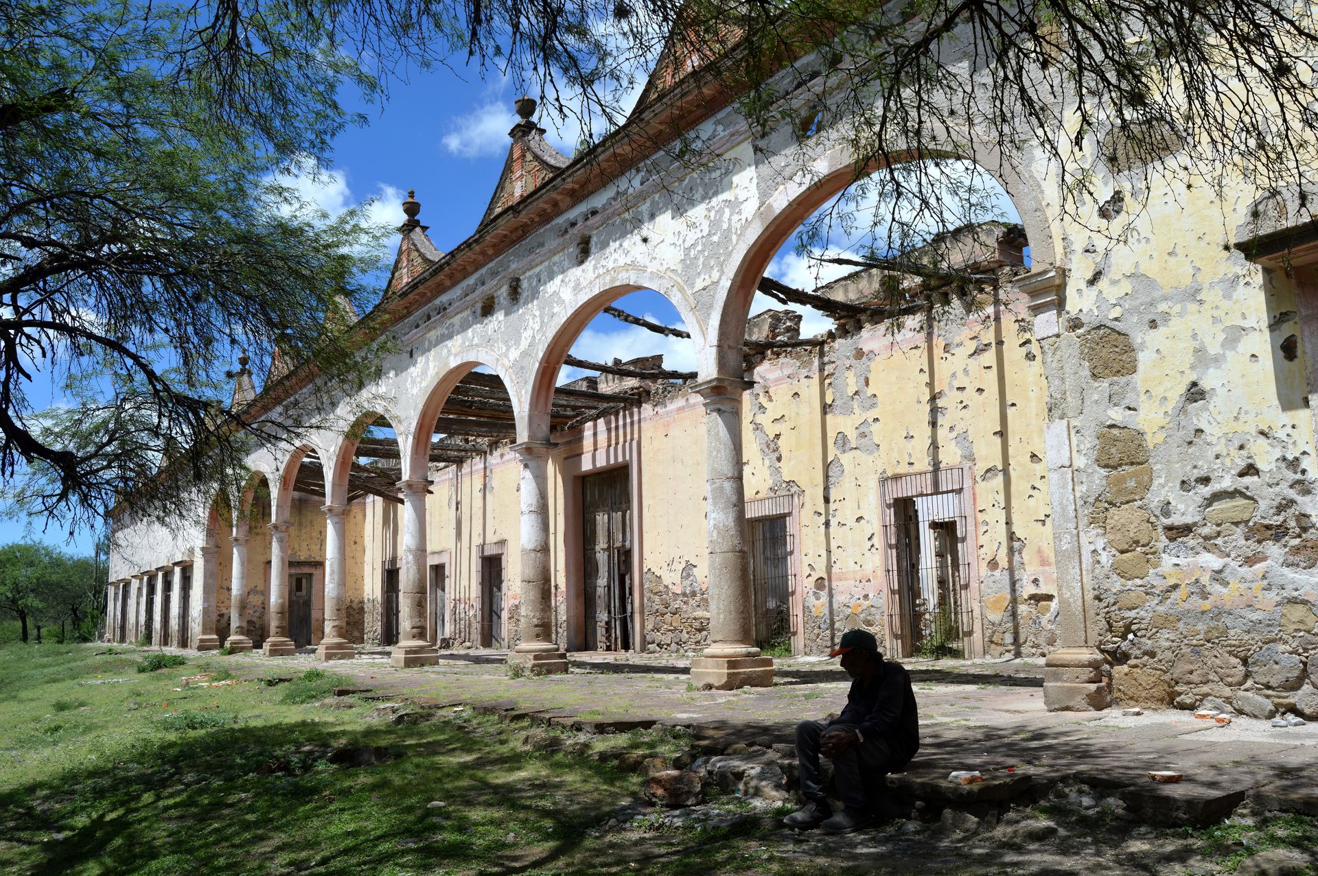 The weathered stone arches of Hacienda Pozo del Carmen beneath a clear blue sky